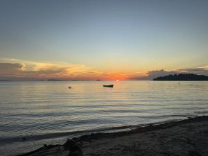 a sunset on the beach with a boat in the water at PROpaganda Guest House in Thongsala