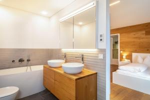 two sinks in a bathroom with a tub and a bedroom at Ferienwohnung Lauterach in Lauterach +16 photos
