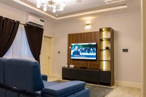 a living room with a blue couch and a flat screen tv at Zilla Luxury - Lifecamp in Abuja