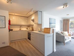 a kitchen with white cabinets and a living room at Lower Deck in Fowey