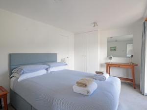 a white bedroom with a bed with towels on it at Lower Deck in Fowey