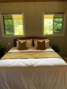 a large bed in a bedroom with two windows at Pradu House 
