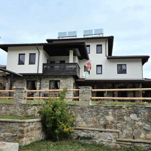 een wit huis bovenop een stenen muur bij Къща за гости МЕЧА СТЪПКА in Gela