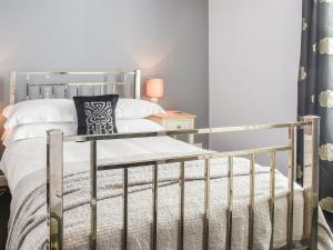 een slaapkamer met een metalen bed met witte kussens bij Fuchsia Cottage in Sea Palling +9 foto's