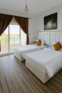 ジッダにあるفيلا الاحلام aの大きな窓付きの客室で、白いベッド2台が備わります。