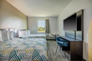 a hotel room with a bed and a desk and a tv at Studio 6 Giddings in Giddings