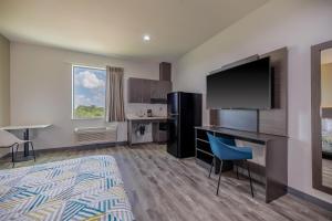 a hotel room with a desk and a flat screen tv at Studio 6 Giddings in Giddings