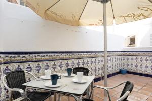a table with chairs and an umbrella in a restaurant at Casa Begines in Vejer de la Frontera