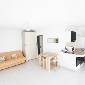 a living room with a table and a kitchen at Olivéa - Écrin fleuri, terrasse & plage à 5 min in Antibes