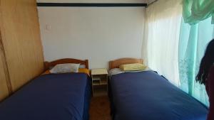 two beds in a small room with a window at Hostal la POSADA in Uyuni +15 photos