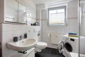een witte badkamer met een wastafel en een wasmachine bij Haus Castellbergblick mit Balkon in Ballrechten +13 foto's