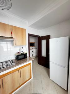 a kitchen with a white refrigerator and a stove at Appartement Tanger Stade ibn batouta in Tangier