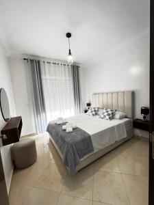 a white bedroom with a large bed and a window at Appartement Tanger Stade ibn batouta in Tangier