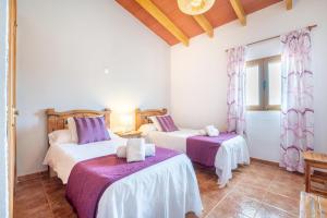 two beds in a room with purple sheets at Can grau petit in Sencelles +17 photos