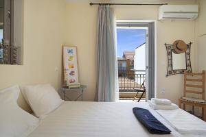 a bedroom with a white bed and a balcony at Casa di sole in Lefkada Town