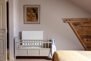a white crib in a bedroom with a painting on the wall at Le Theureau Gîte voor 6 personen in Millay +17 photos
