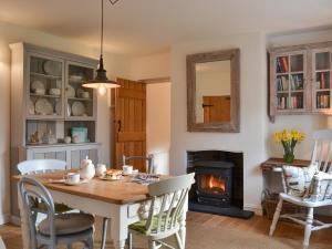 a dining room with a table and a fireplace at Grattan Cottage in Bow