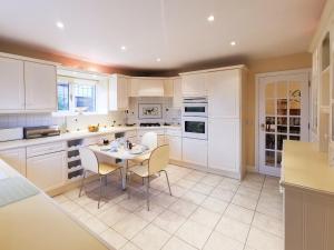 a kitchen with white cabinets and a table and chairs at Holly Barn in Selattyn +17 photos