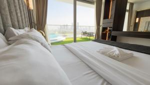 ドバイにあるHighend Azure 1BR Sea View and Private Beach with Pool Accessの大きな窓のある部屋にある白いベッド