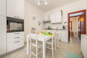 una cucina bianca con tavolo e sedie bianchi di Casa Clà a Villasimius