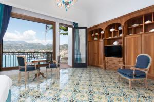 a room with a bed and a tv and chairs at Hotel La Tonnarella in Sorrento