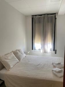a white bed in a room with two windows at Hostal Collsacabra in L’ Esquirol