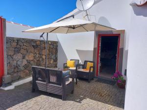 a patio with chairs and an umbrella at Casa das Cales in Angra do Heroísmo