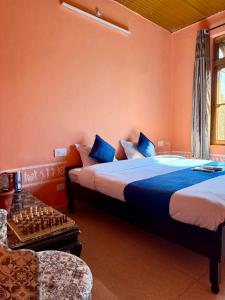 ビーアにあるSabhyata Stays Birのベッドが2つとテーブルの上にチェス盤がある寝室