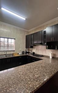 a kitchen with black cabinets and a granite counter top at Madeley House Unit 2 near Oliver Tambo Airport in Boksburg