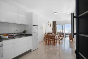 Una cocina con gabinetes blancos y una mesa con sillas. en Callao Beach 1, en Arrieta
