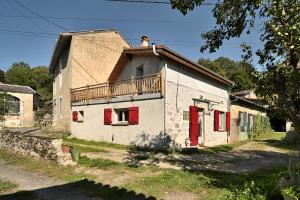 an old house with red doors and a balcony at Maison Vallée de Barousse in Barbazan