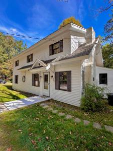 a white house with a lawn in front of it at Warm Cabin Escape near Loon Mountain, Ice Castles and Cannon Mountain in Woodstock