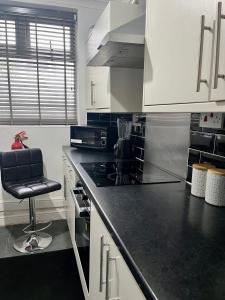 eine Küche mit weißen Schränken und einer schwarzen Arbeitsplatte in der Unterkunft Home from home in Southend-on-Sea