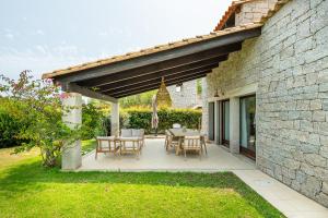a patio with a table and chairs and a building at Villa Bouganville Cala Sinzias in Cala Sinzias