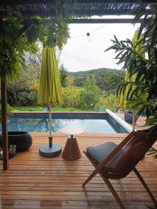 a wooden deck with a chair and a table and a pool at A l'Orée des Oliviers in Venterol