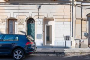 a blue car parked in front of a building with a green door at Dimora Bianca in San Cesario di Lecce