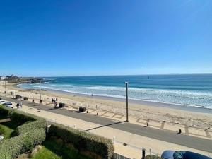 a beach with people walking on the sand and the ocean at Quiberon - Grand T2 - Balcon Sud - 70m² - Plage & Centre - Parking & WIFI - FR-1-478-203 in Quiberon