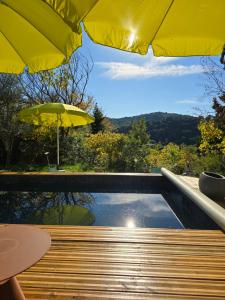 a swimming pool with an umbrella and a table at A l'Orée des Oliviers in Venterol