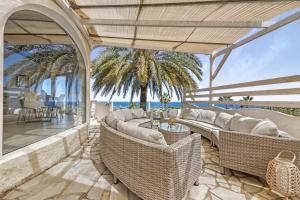 an outdoor patio with wicker furniture and a palm tree at Adriana in Denia