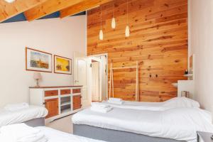 a room with three beds and a wooden wall at Beautiful house in nature for 20 people in Wetering