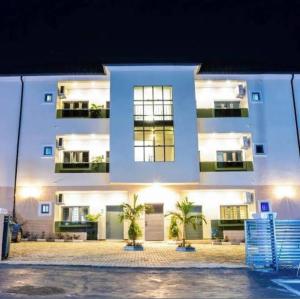 a white building with two palm trees in front of it at Zilla Luxury - Lifecamp in Abuja