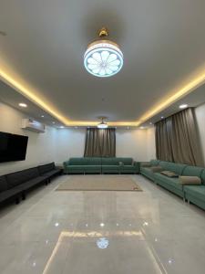 a large living room with green couches and a television at Hajir Garden House in Muşayna‘ah