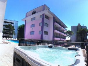 a hot tub in front of a pink building at Residenz Regent Beach Wohnung Living für 4 Personen in Bibione