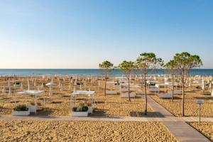 a sandy beach with white umbrellas and the ocean at Residenz Regent Beach Wohnung Living für 4 Personen in Bibione