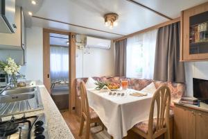 eine Küche und einen Tisch mit einem weißen Tischtuch in der Unterkunft Feriendorf Oasi Mobilehome Maui für 5 Personen in Sottomarina