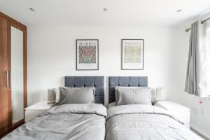two beds in a room with white walls at Karazo LTD - Luxurious contractor and family friendly 4 bedroom in Croydon with Parking in Croydon