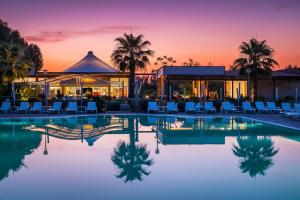 un complexe avec une piscine entourée de chaises et un bâtiment dans l'établissement Feriendorf Le Tamerici Mobilehome Costa Rei für 6 Personen, à Marina di Cecina