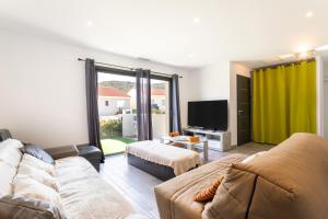 een woonkamer met een bank en een flatscreen-tv bij Rascola villa piscine 4 étoiles in Le Boulou