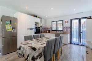 een keuken met een tafel met stoelen en een koelkast bij Rascola villa piscine 4 étoiles in Le Boulou