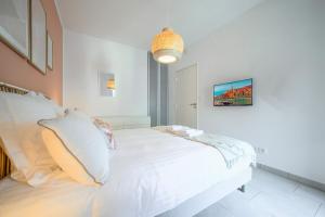 een witte slaapkamer met een wit bed en een hanglamp bij Le COQ Wagner - Garage -AC- Swimming pool in Menton